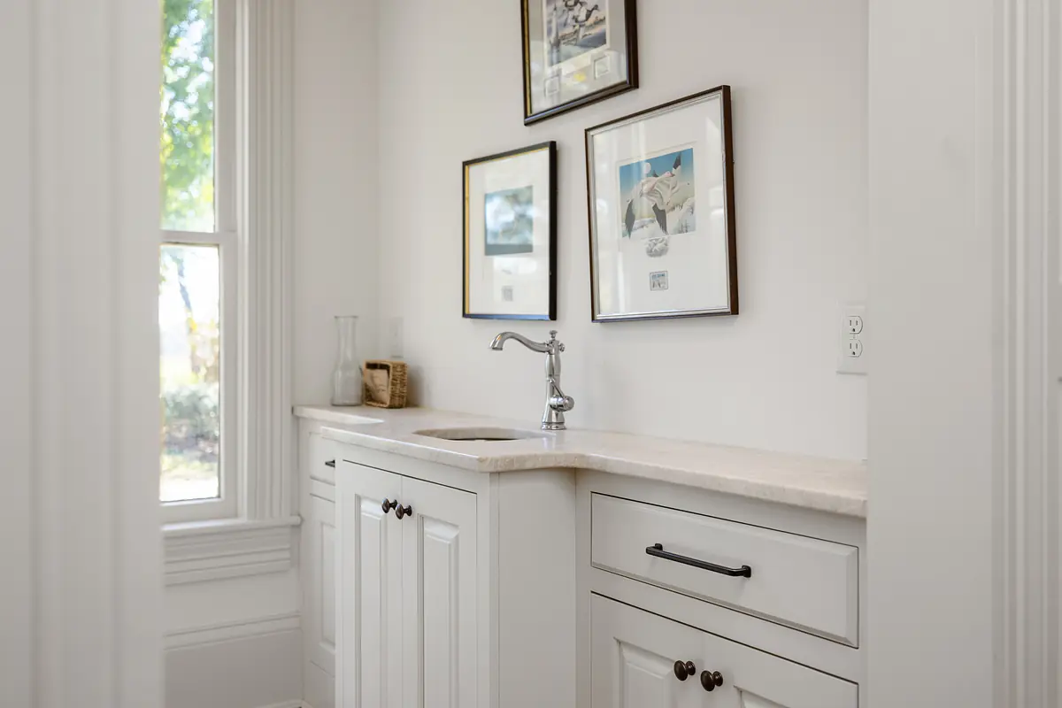 Kitchen with white cabinetry, light countertop, single basin sink, and framed artwork.