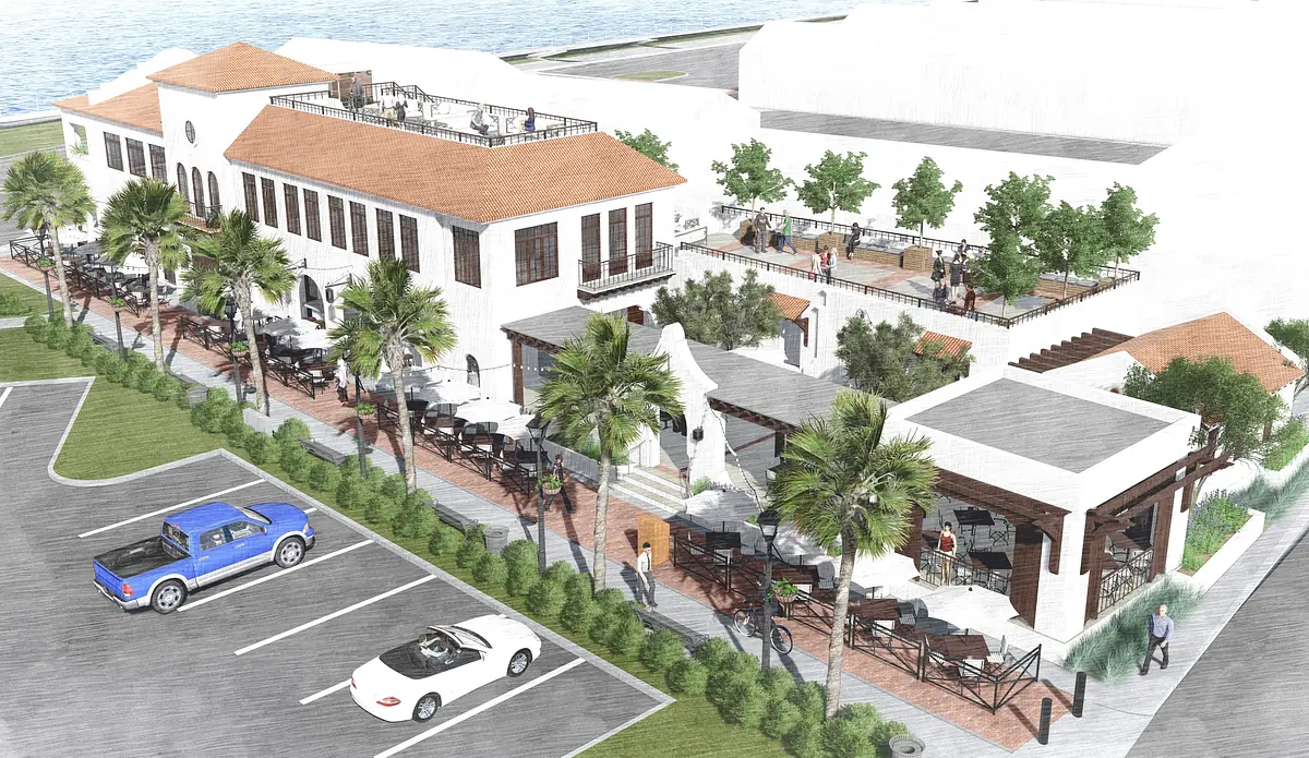 Exterior view of a two-story building with patios, palm trees, and parked vehicles.