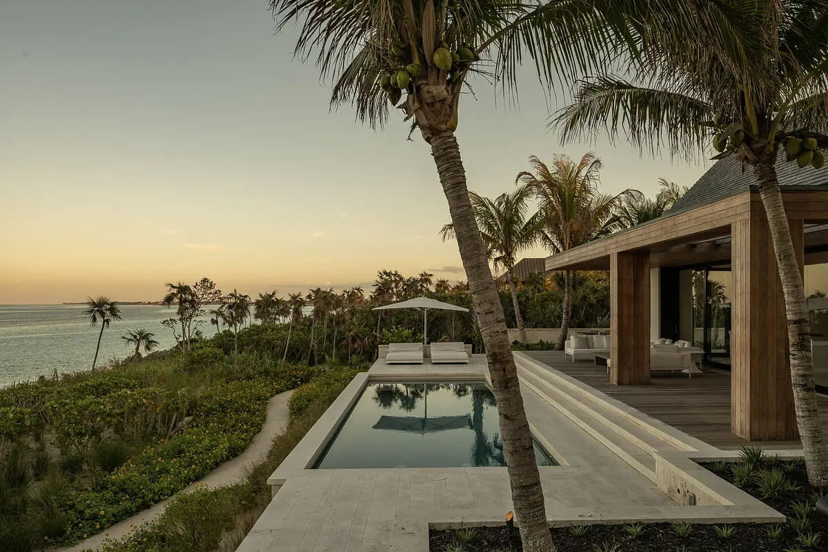 Exterior rear with swimming pool, lounge chairs, shaded seating area, palm trees, and tropical landscaping.