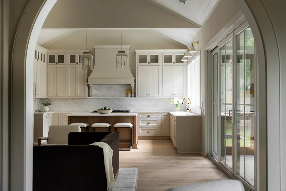 Kitchen with white cabinets, marble backsplash, wooden countertops, bar stools, and large glass doors