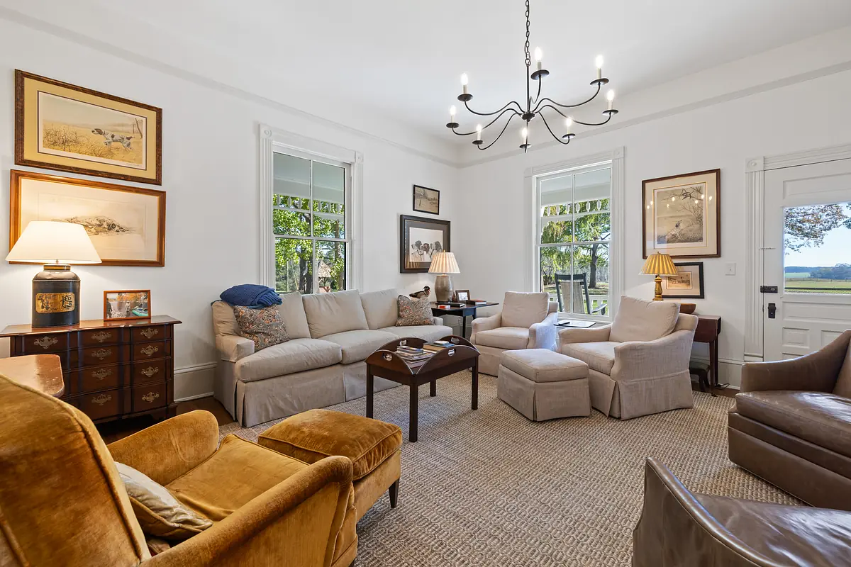 Living room with light sofa, brown armchair, beige chairs, dark coffee table, and framed artworks