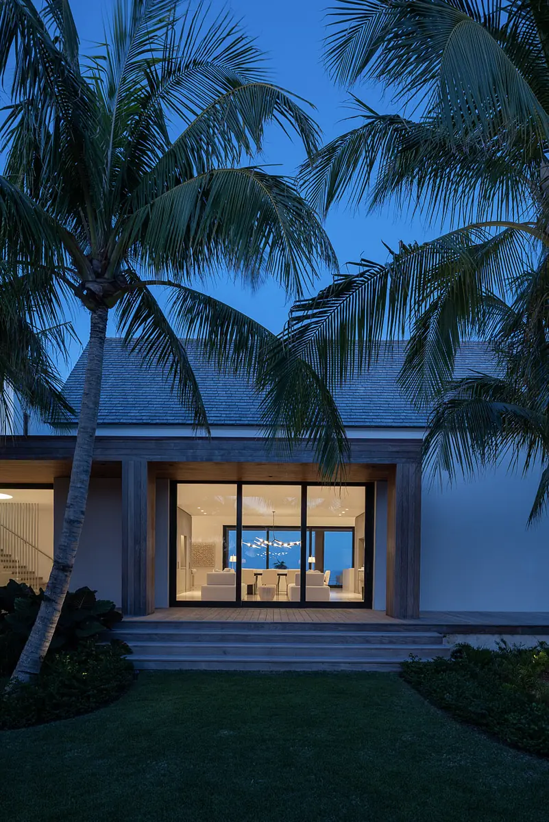 Exterior front view of modern house with palm trees, sliding glass doors, and wooden deck