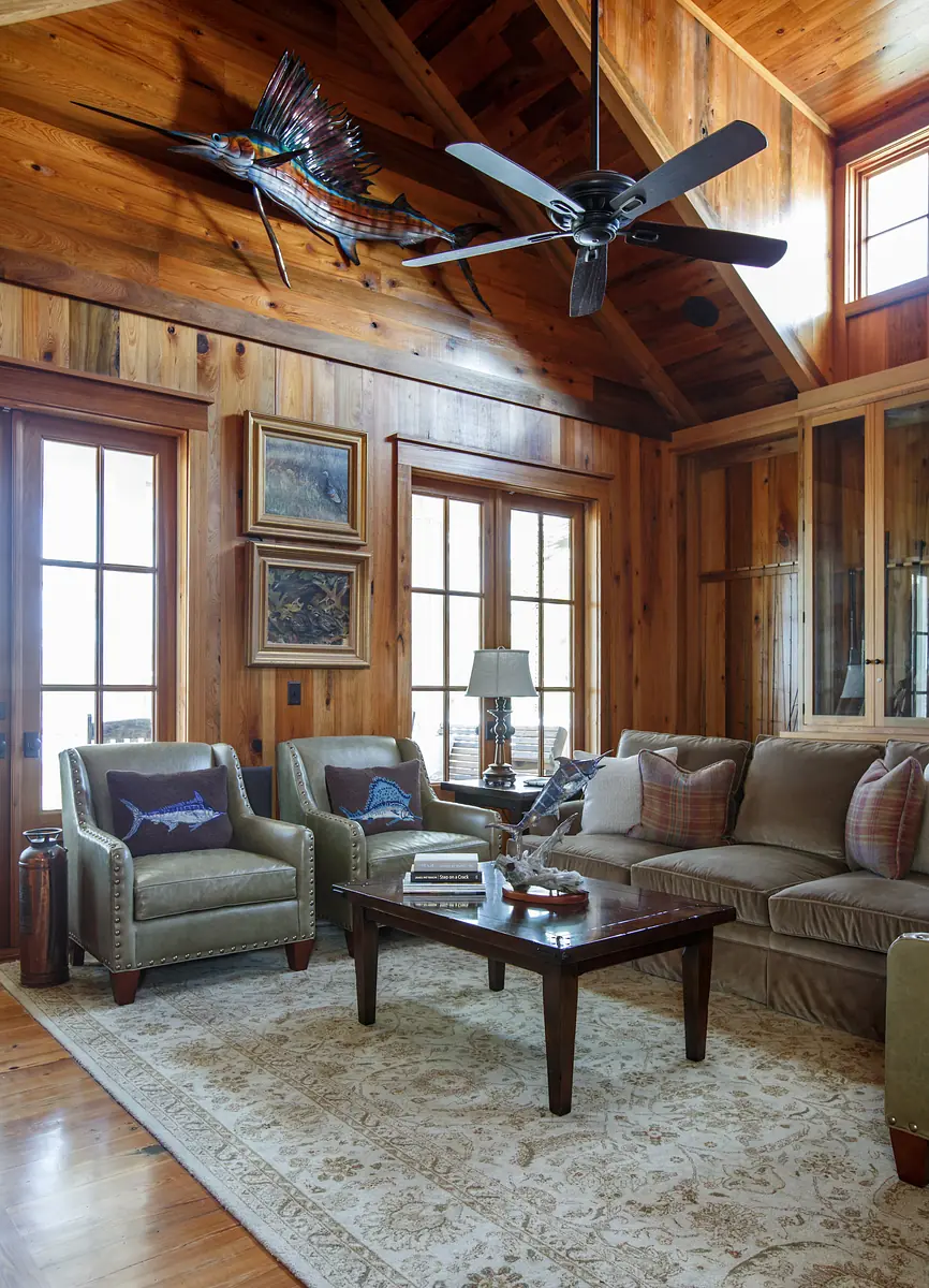 Living room with beige sofa, armchairs, wood coffee table, area rug, wall art, and wood paneling.