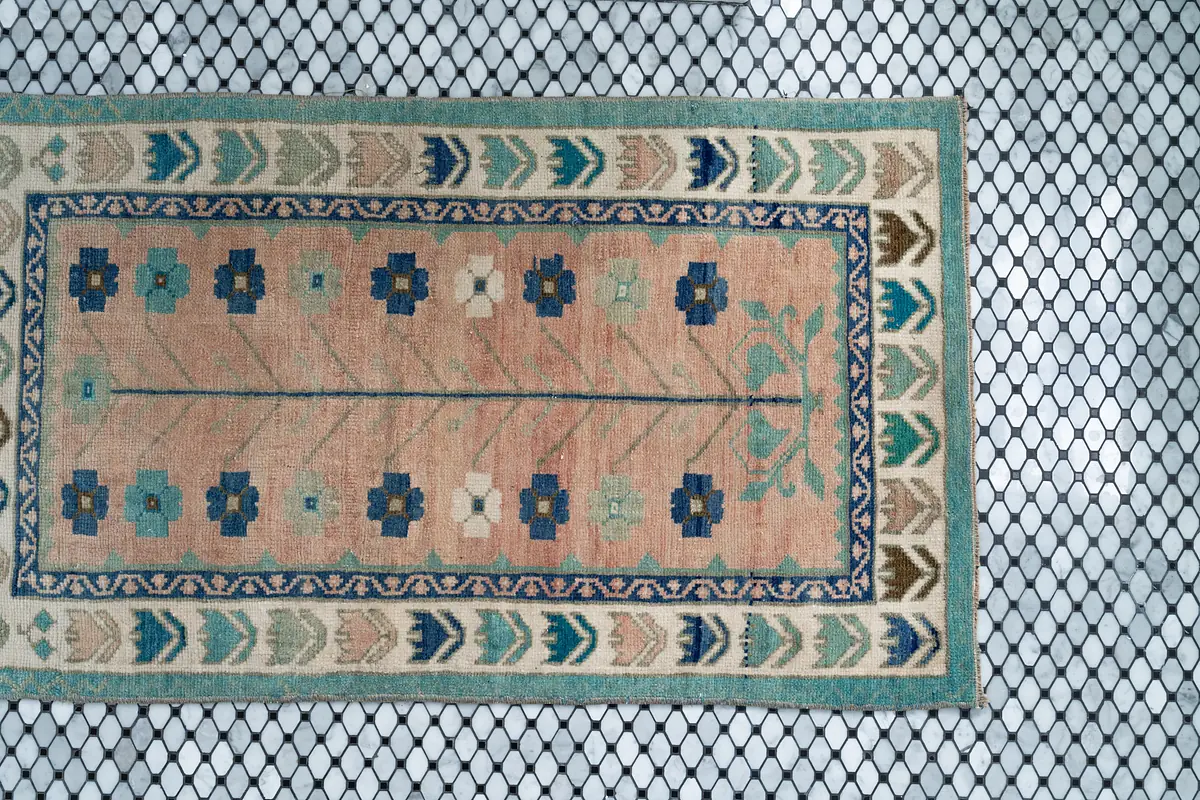 Area rug with floral and geometric pattern on black hexagonal tile floor.