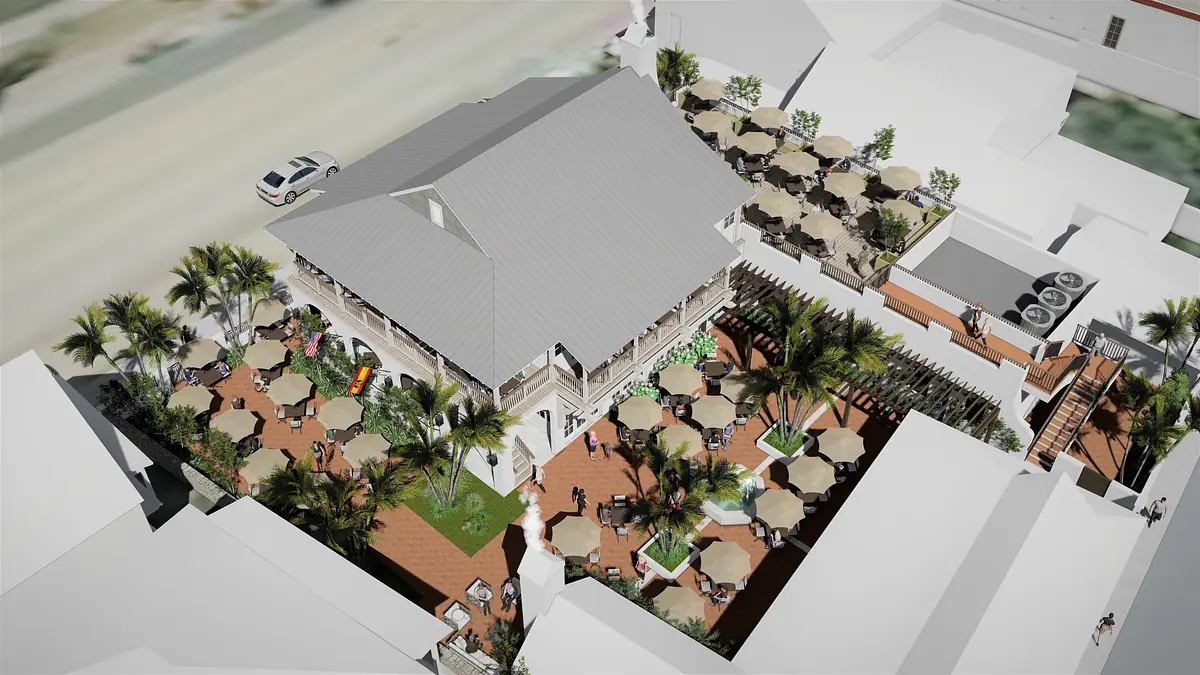 Aerial view of a building with outdoor seating, palm trees, and a sloped roof.