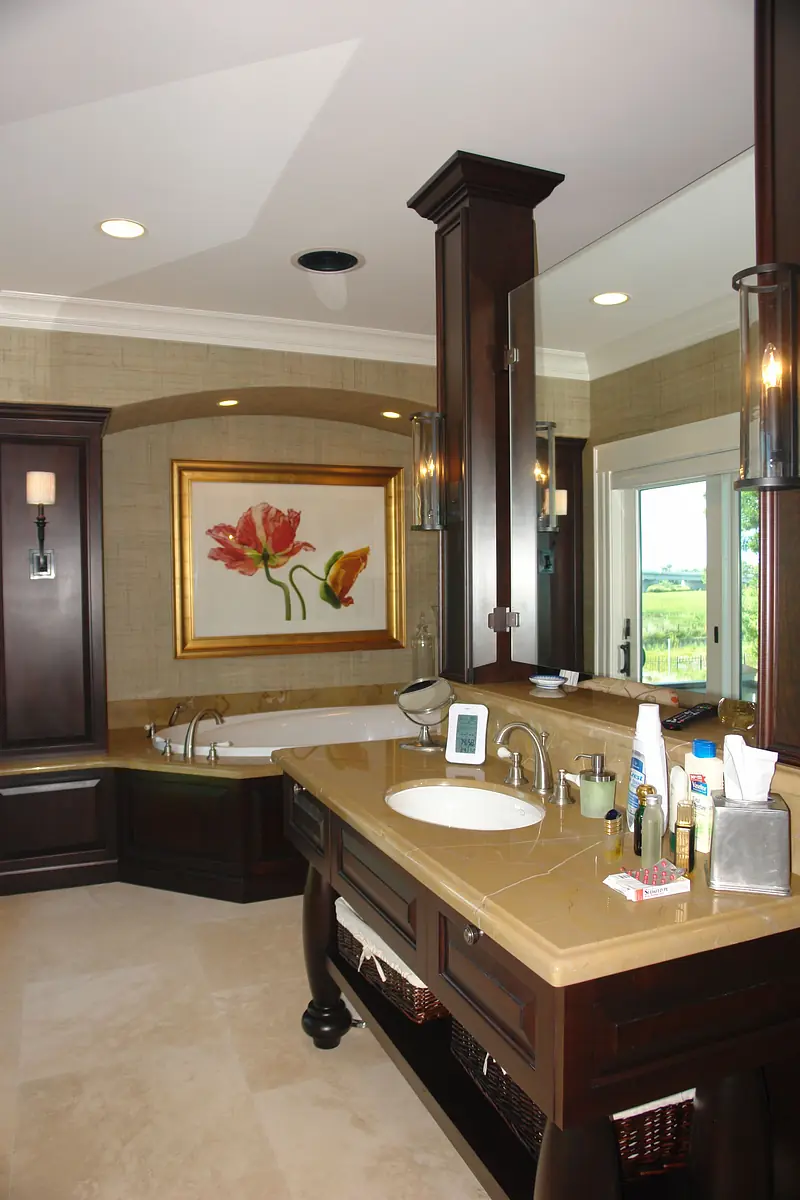 Bathroom with dark wood vanity, large mirror, freestanding bathtub, and beige tile flooring.
