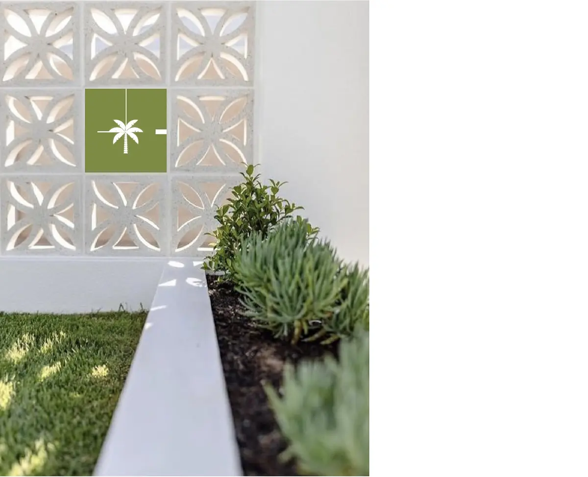 Garden area with succulent plants, decorative wall cutouts, and grass in the foreground.