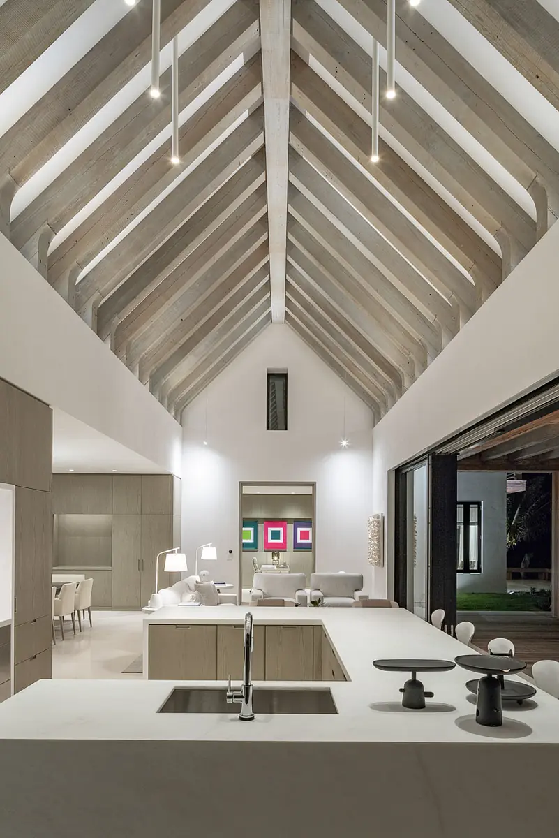 Kitchen with central island, concrete counters, wood cabinetry, exposed beams, and large windows