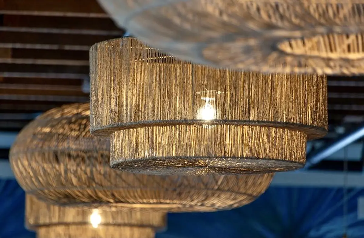 Woven pendant lights with natural color hanging from a wooden ceiling, showcasing a layered texture.
