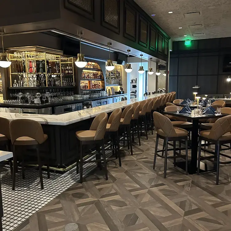 Dining room with bar seating, marble-topped bar, geometric tile floor, tables, and pendant lights.