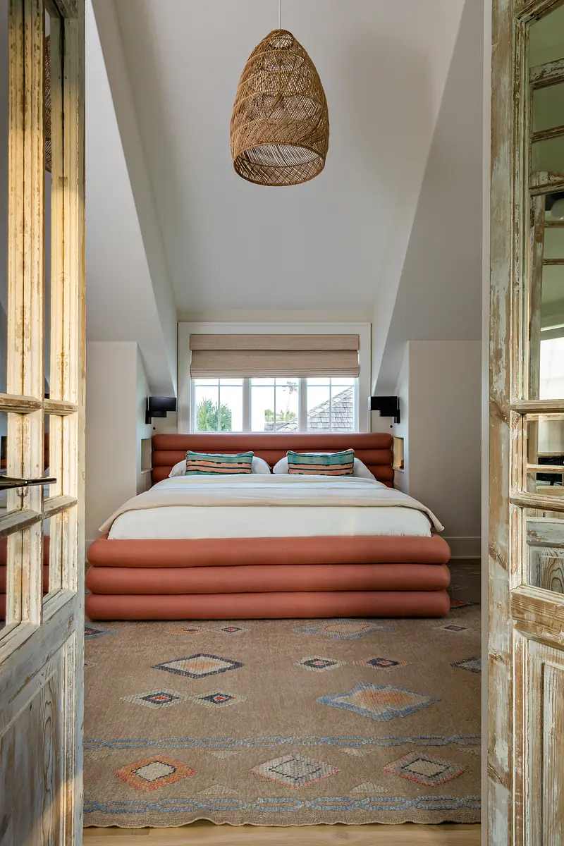 Bedroom with large bed, patterned rug, sloped ceilings, and glass doors leading inside