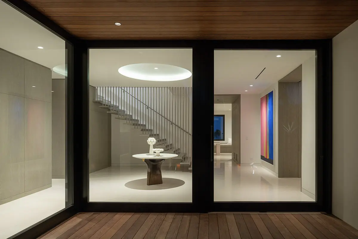 Foyer with round table, open staircase, glass doors, and artworks on the walls