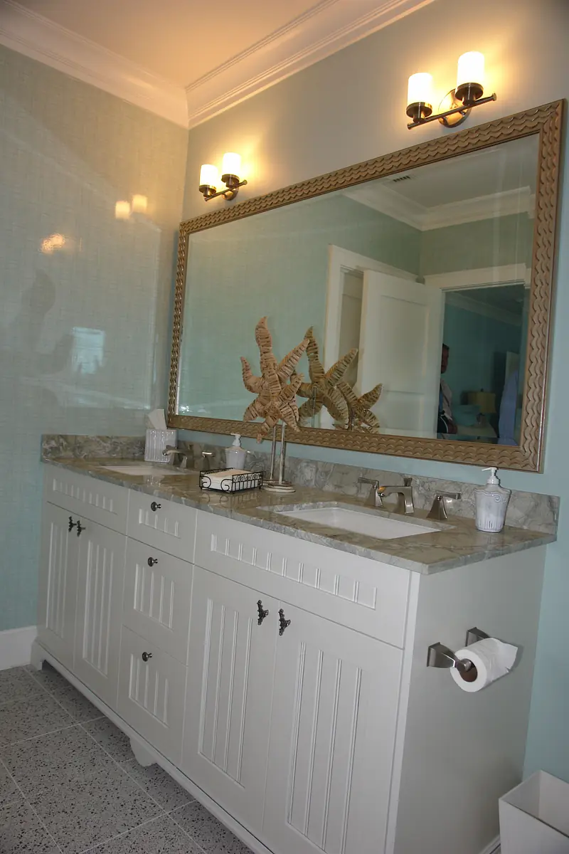 Bathroom with dual sinks, marble countertop, large mirror, and light blue walls.