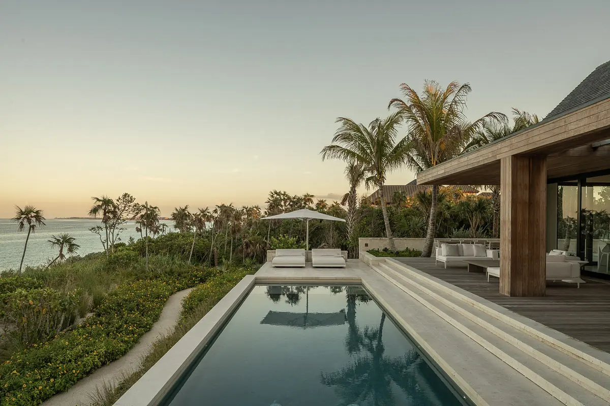 Outdoor space with swimming pool, palm trees, lounge chairs, and covered dining area with ocean view.