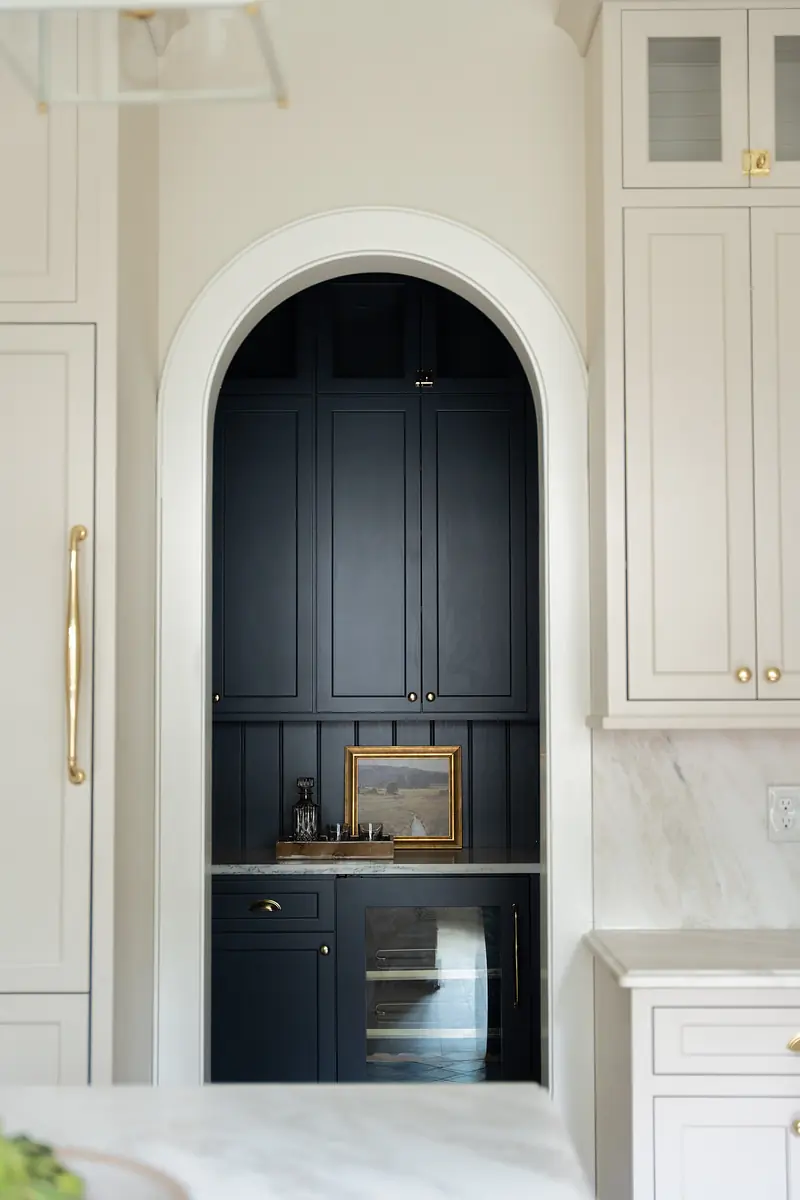 Kitchen with navy cabinets, marble countertop, arched opening, glass doors, and a built-in wine cooler.