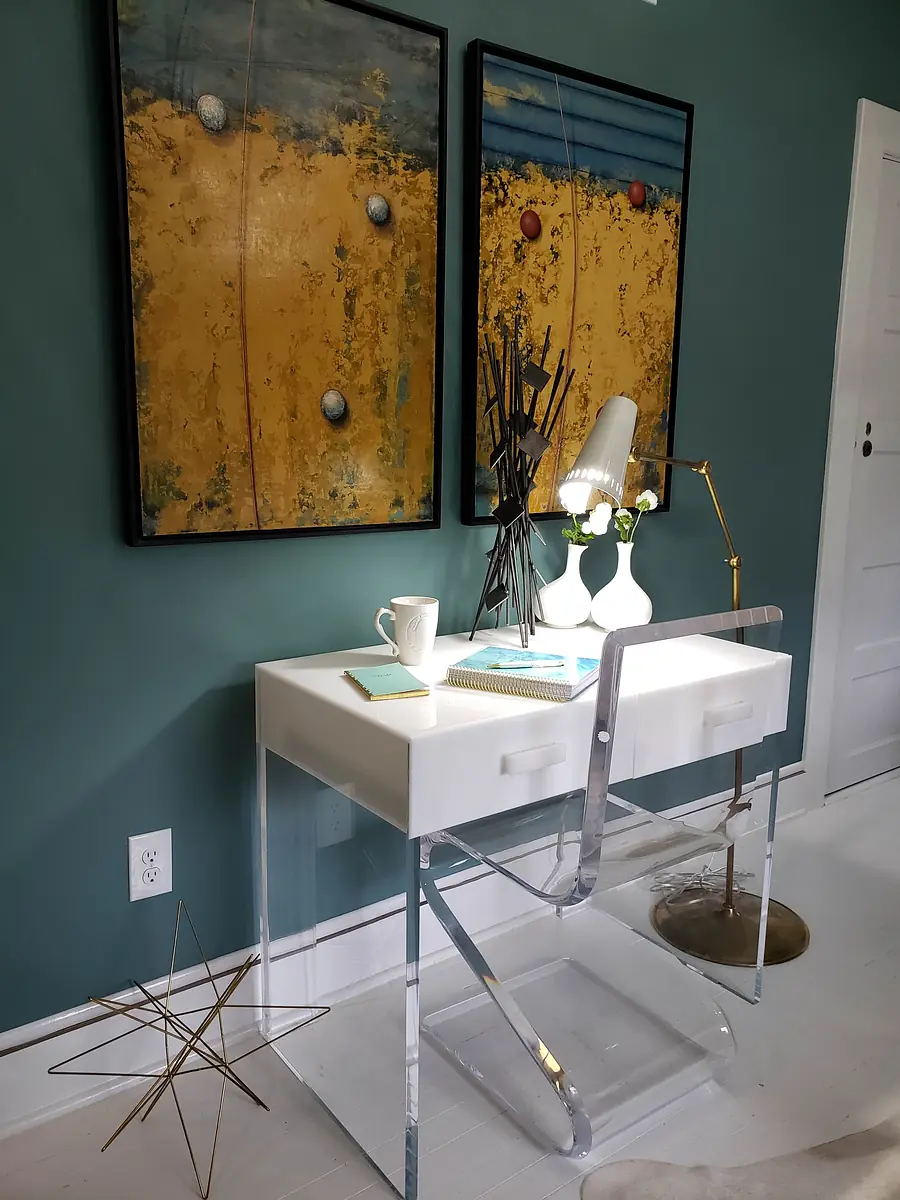 Workspace with white desk, gold floor lamp, abstract paintings, and decorative star sculpture.