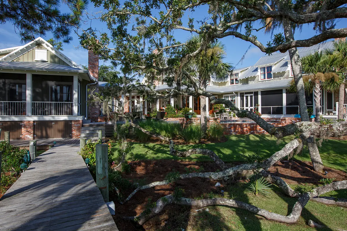 Exterior view of homes with porches, walkway, garden, palm trees, and a brick chimney