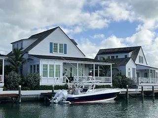 Waterfront view of two white houses with porches and a docked boat.