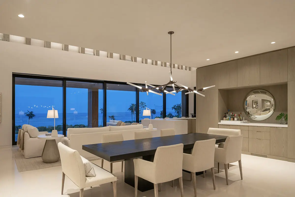 Dining room with dark wood table, upholstered chairs, sideboard, and large glass doors.