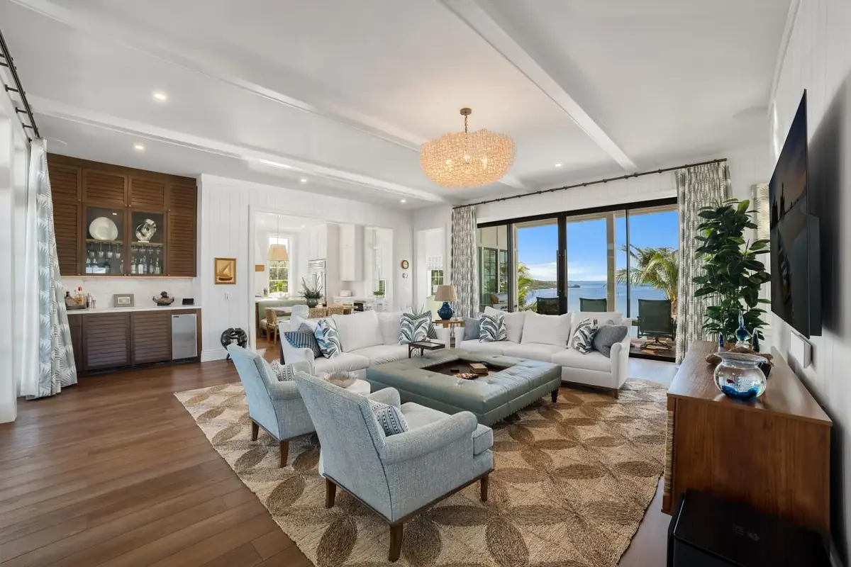 Living room with two white sofas, blue armchairs, brown coffee table, large area rug, and glass sliding doors.
