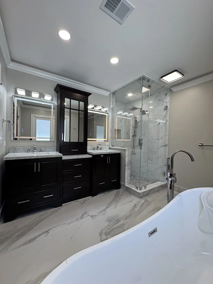 Bathroom with glass shower, freestanding bathtub, dark wood vanity, and marble flooring.