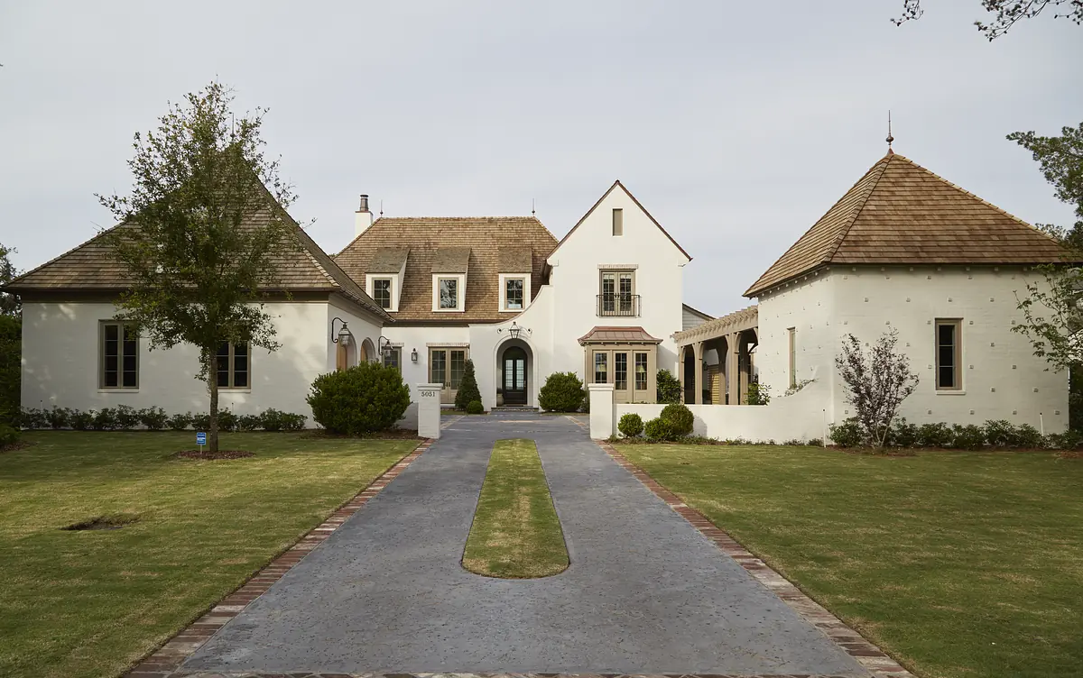 Front exterior view of a house with white walls, multiple gables, stone pathway, and landscaped yard.