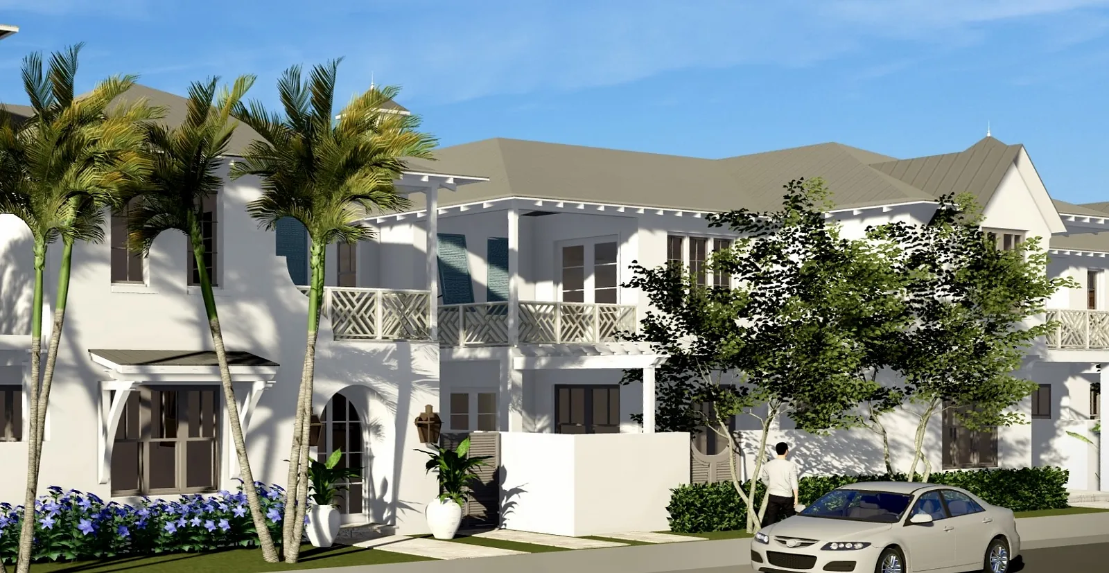 Exterior view of a house with white facade, palm trees, and landscaped front yard with flowers and a car.