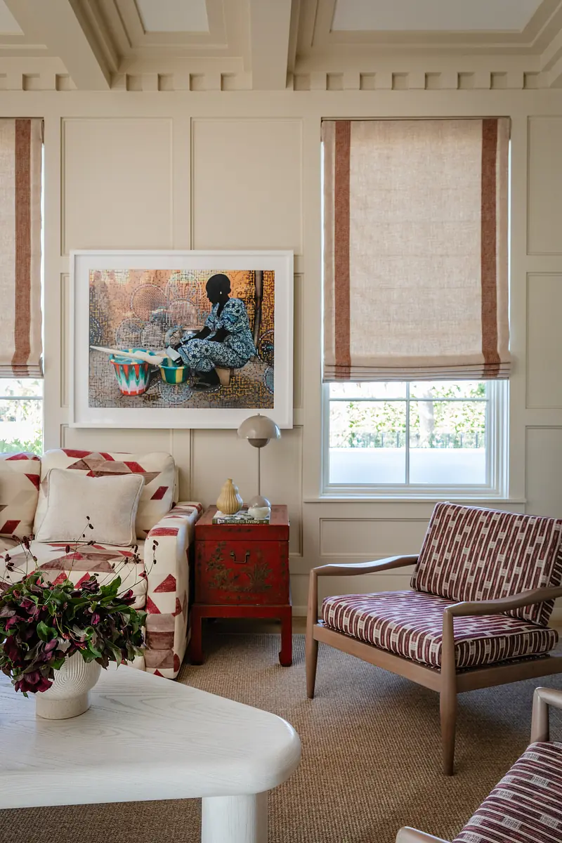 Living room with patterned sofa, striped chair, coffee table, artwork, and woven rug.