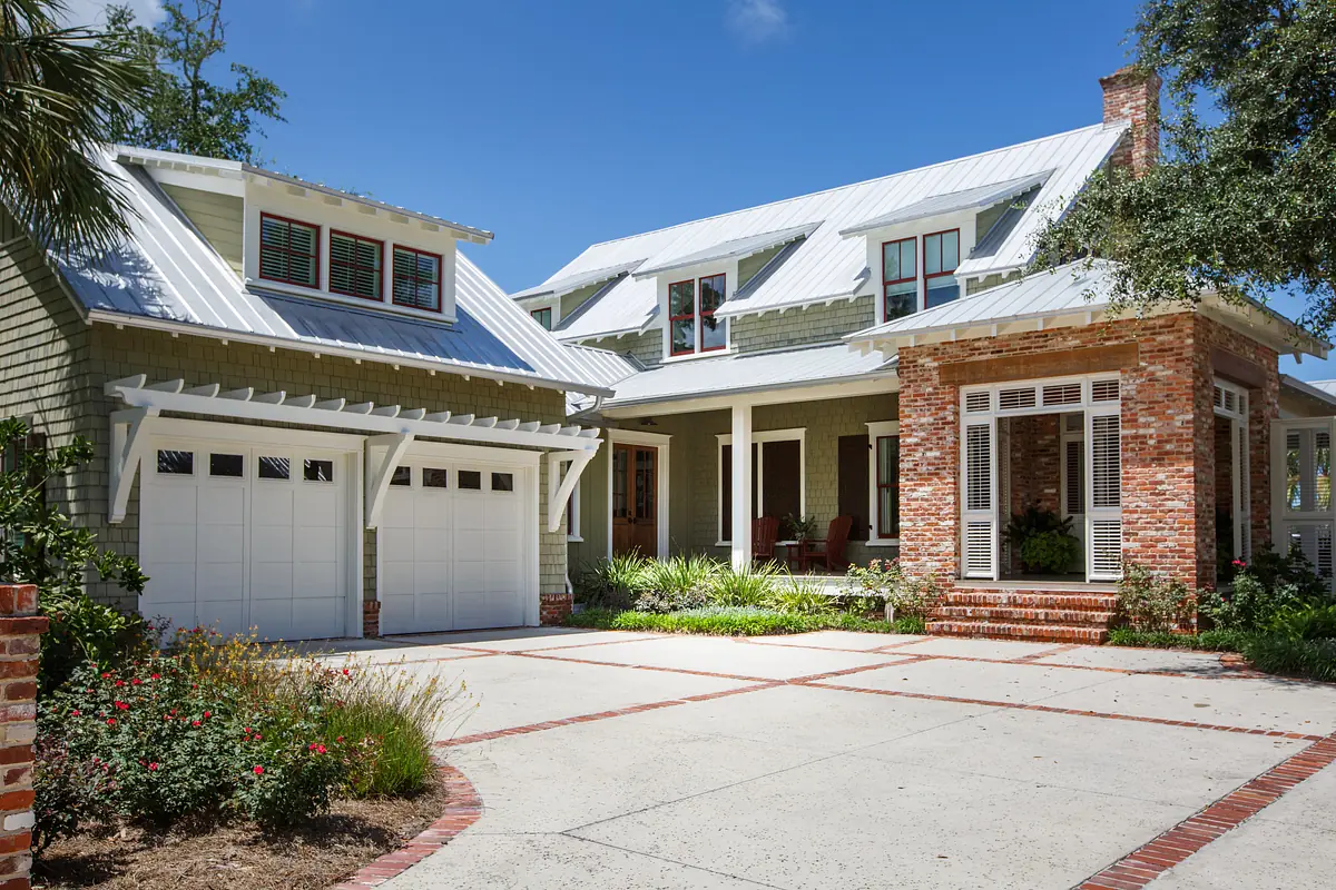 Front exterior with two-story house, metal roof, garage, porch, and landscaped garden.