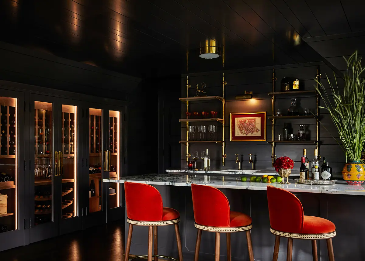 Bar area with marble countertop, red stools, black cabinetry, and wine storage.