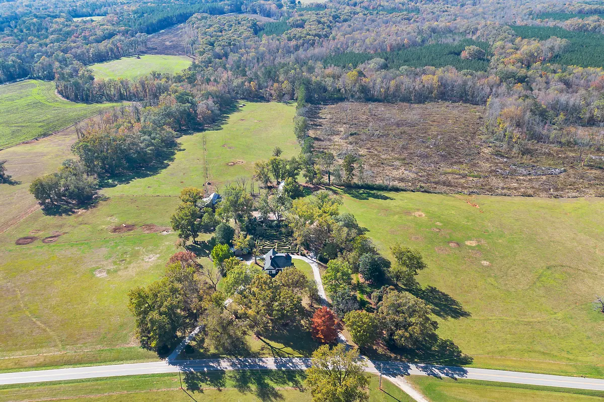 Aerial view of a rural property with house, trees, and open fields.