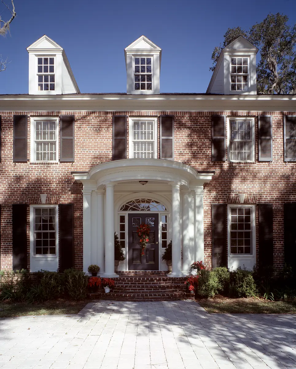 Front exterior with brick house, columns, shutters, dormer windows, and landscaped walkway.