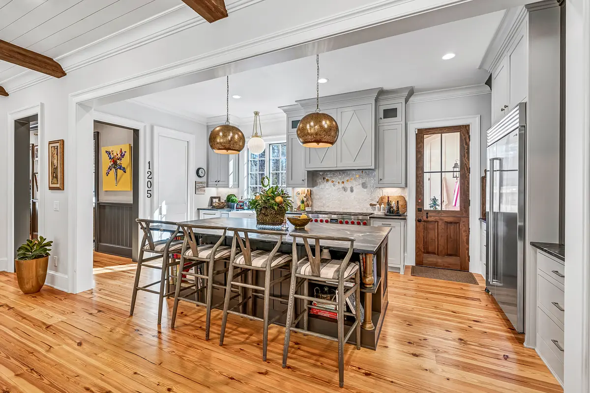 Kitchen with island seating, stainless steel appliances, gray cabinets, and wood floor.