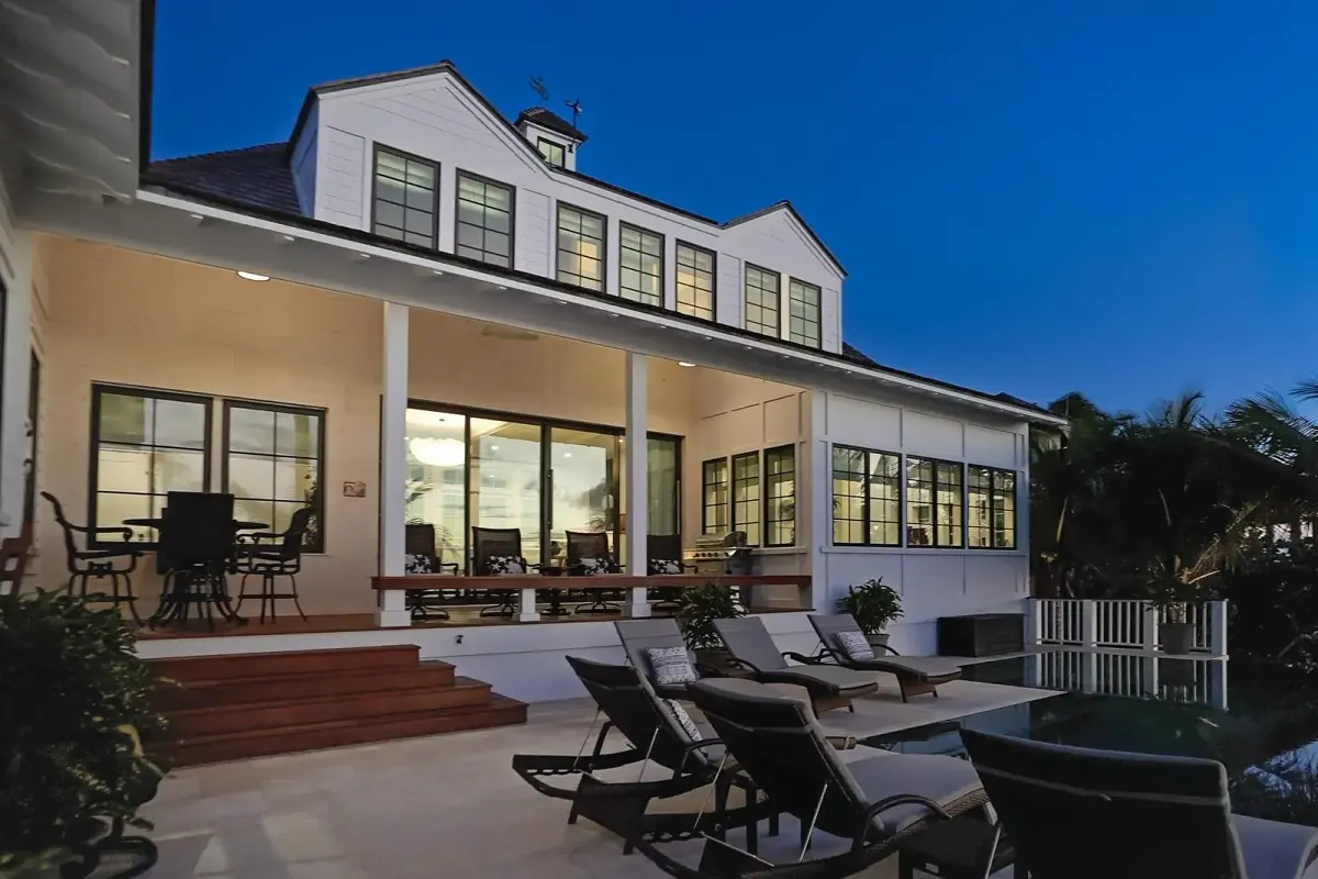 Rear exterior with swimming pool, chaise lounges, patio area, large windows, and staircase.