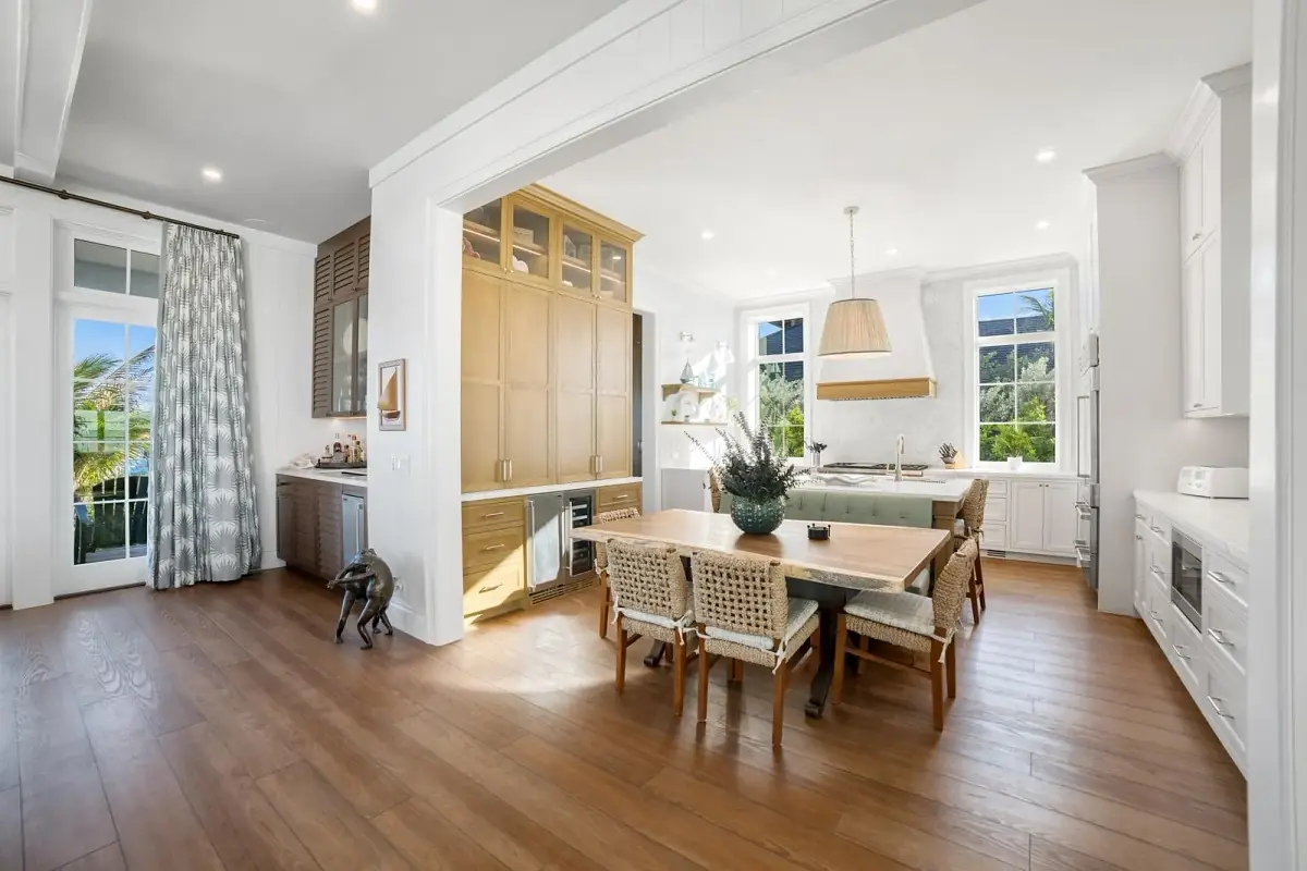 Kitchen with wood cabinetry, island, dining table, woven chairs, multiple windows, and a pendant light.