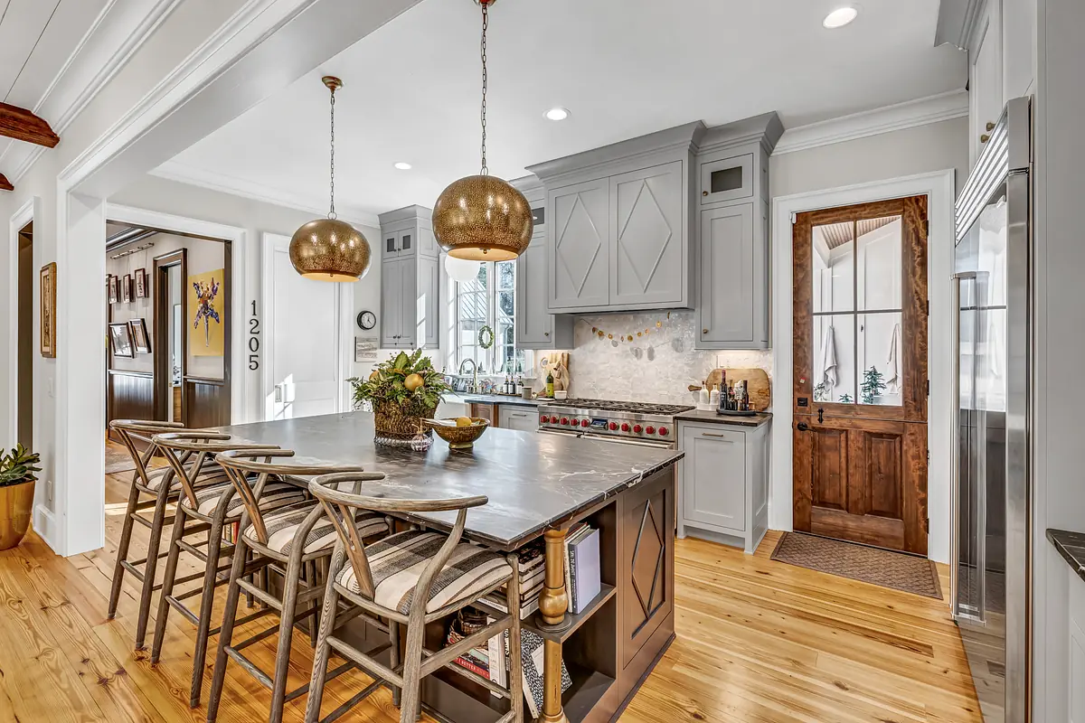 Kitchen with island, gray countertop, bar stools, wooden cabinetry, and stainless steel appliances.