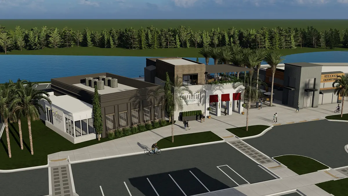 Exterior view of a building complex with diverse structures, parking spaces, palm trees, and a water body.