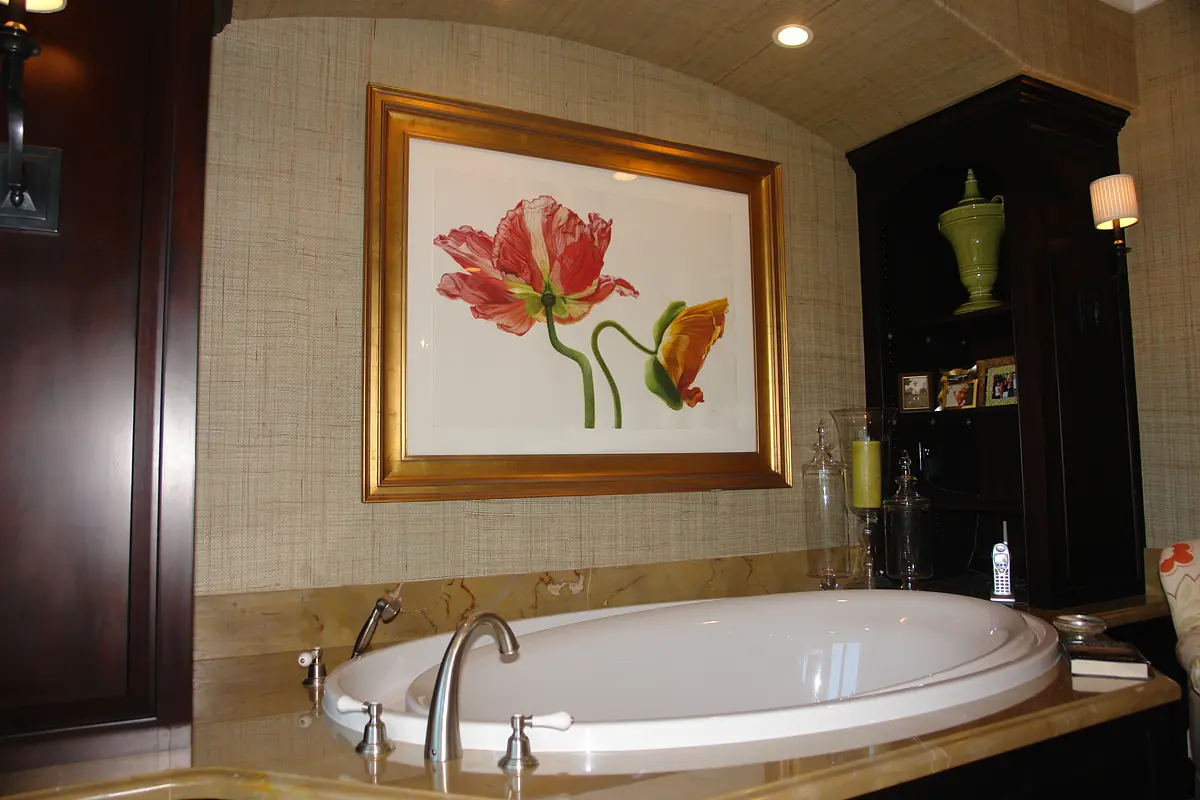 Bathroom with freestanding bathtub, floral artwork, dark cabinetry, and textured walls.