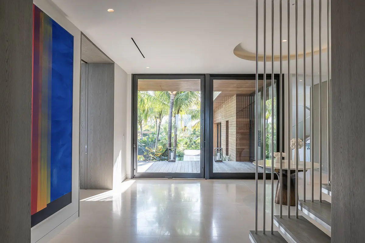 Foyer with large glass doors, round table, abstract painting, and polished floor