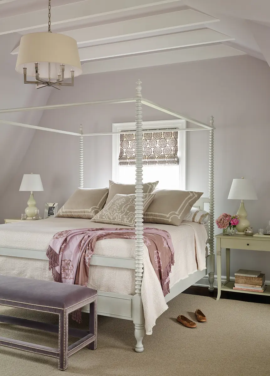 Bedroom with four-poster bed, lavender throw, nightstands, lamps, and a bench at the foot