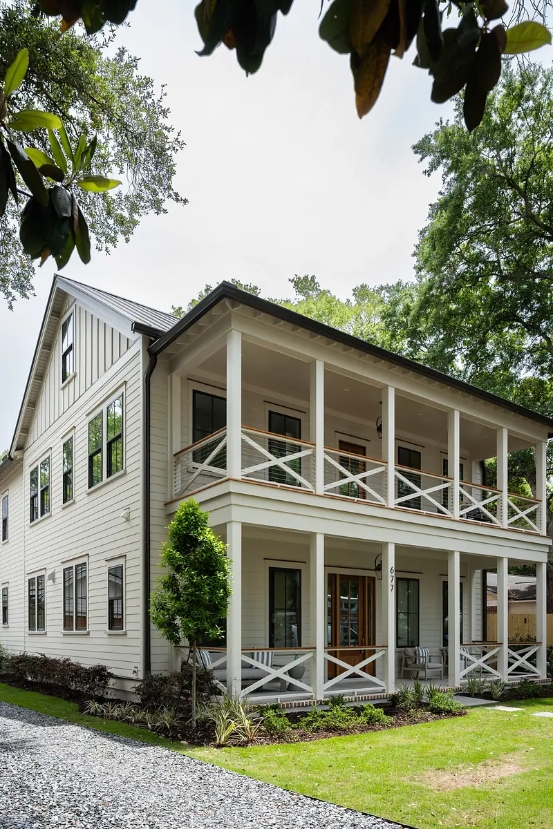 Front view of a two-story house with a white exterior, porch, and landscaped yard.