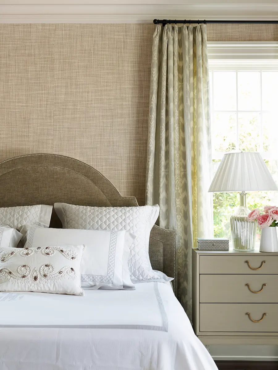 Bedroom with upholstered headboard, white bedding, nightstand, lamp, and window with curtains