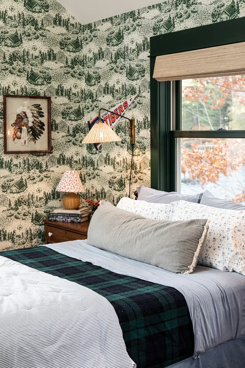 Bedroom with bed, nightstand, lamp, and green patterned wallpaper.