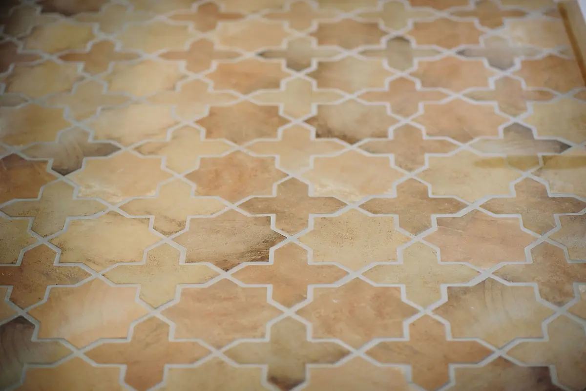Tile floor with geometric star pattern in warm tones of orange and beige.
