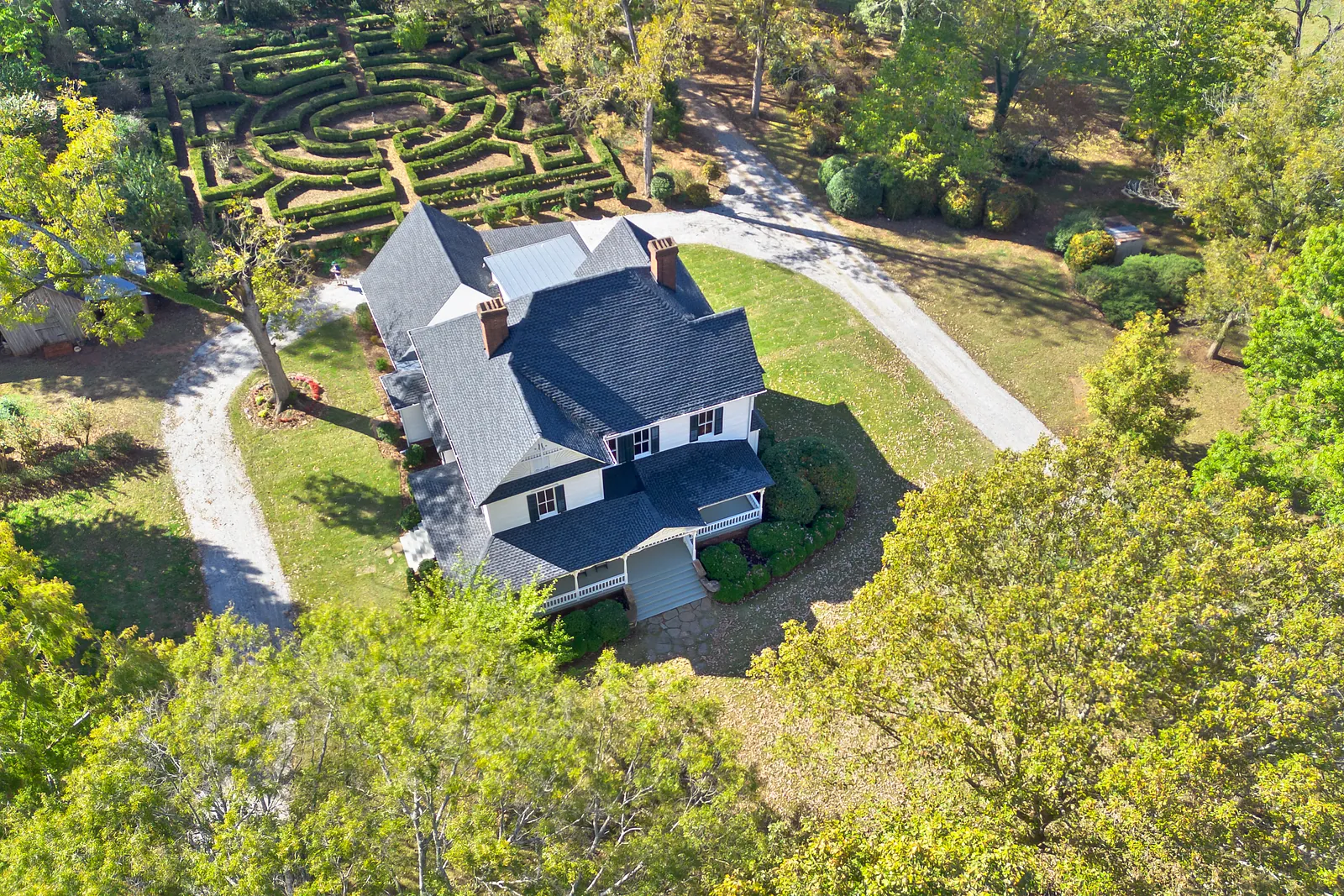 Aerial view of a house with dark gray roof, white siding, and landscaped front yard.