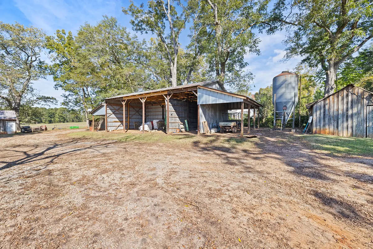 Outdoor farm setting with large barn, grain silo, and smaller sheds.