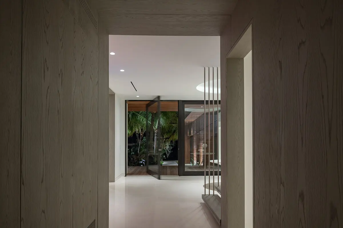 Hallway with wood paneling, glass door, recessed ceiling lighting, and smooth flooring.