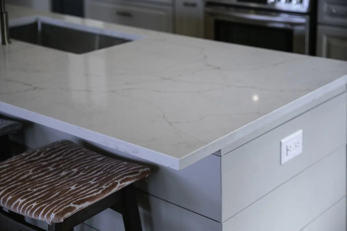 Kitchen with stone countertop, undermount sink, wooden stool, and stainless steel appliances