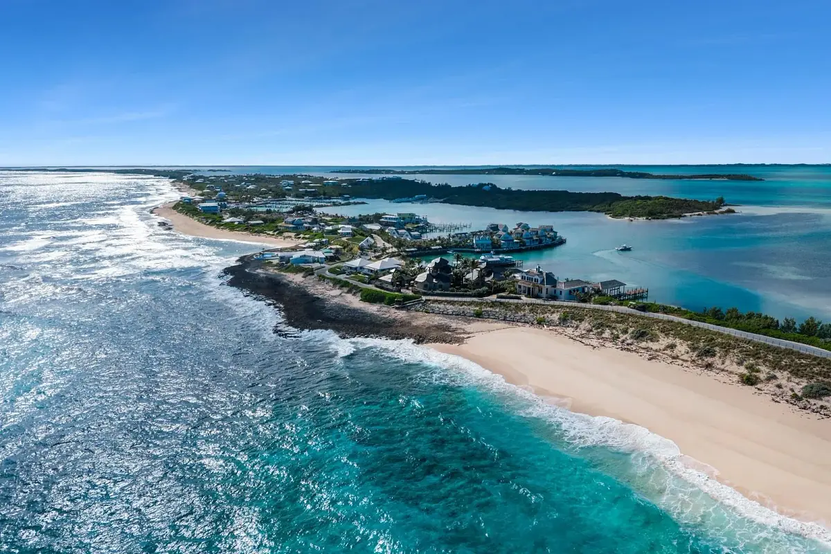 Aerial view of a coastal area with sandy beaches, turquoise ocean, houses, and small boats.
