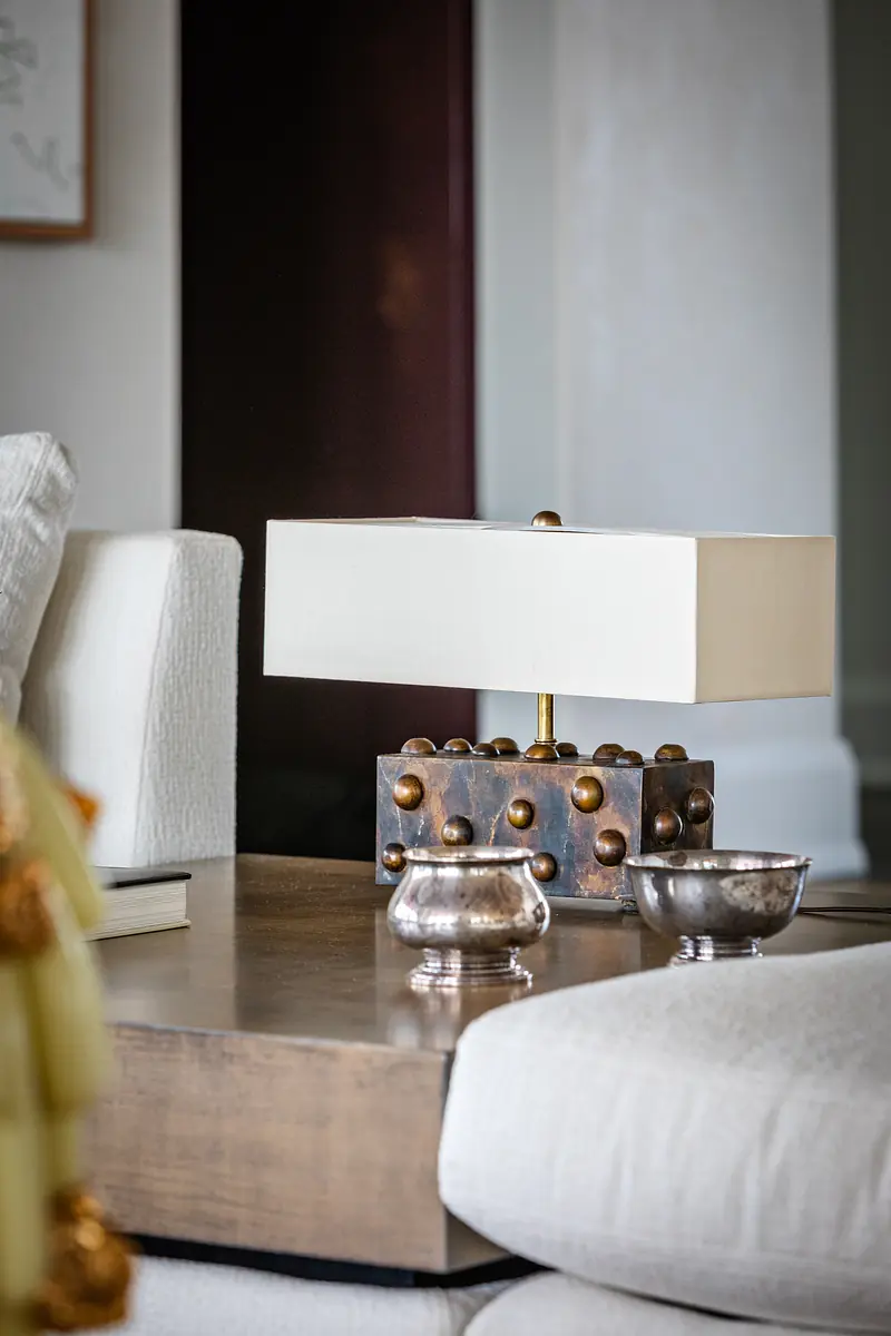 Indoor setting with coffee table, decorative lamp, small accessories, and a light-colored sofa